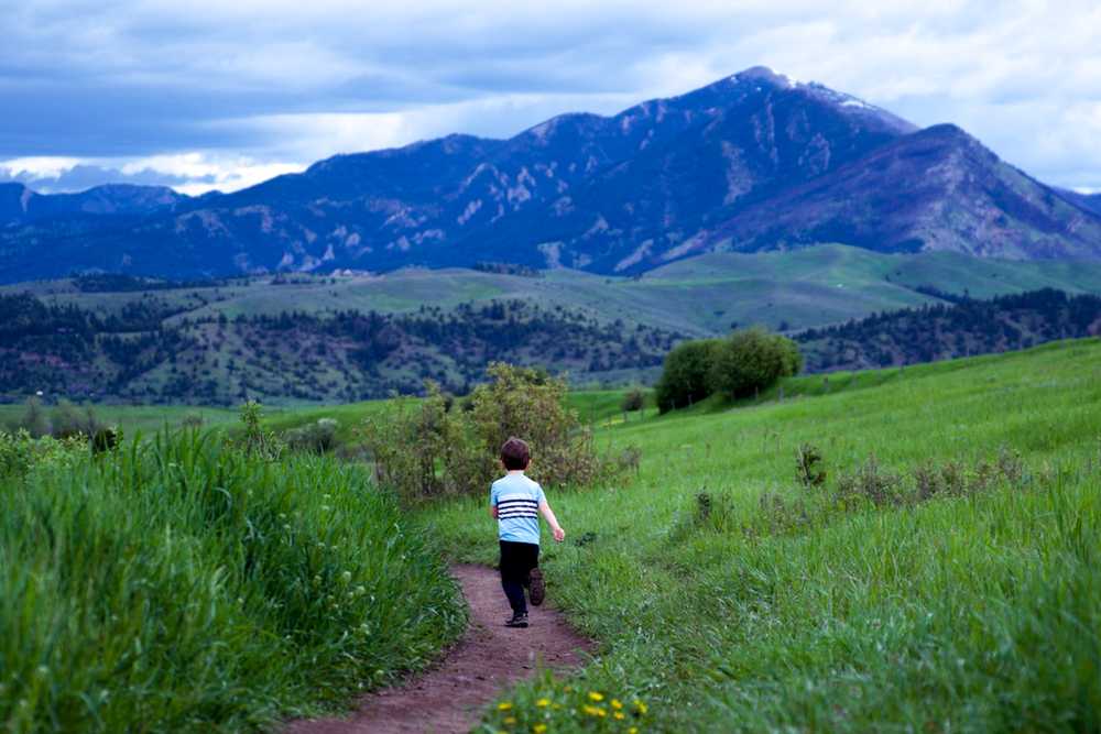 child running on trail with mountains in background